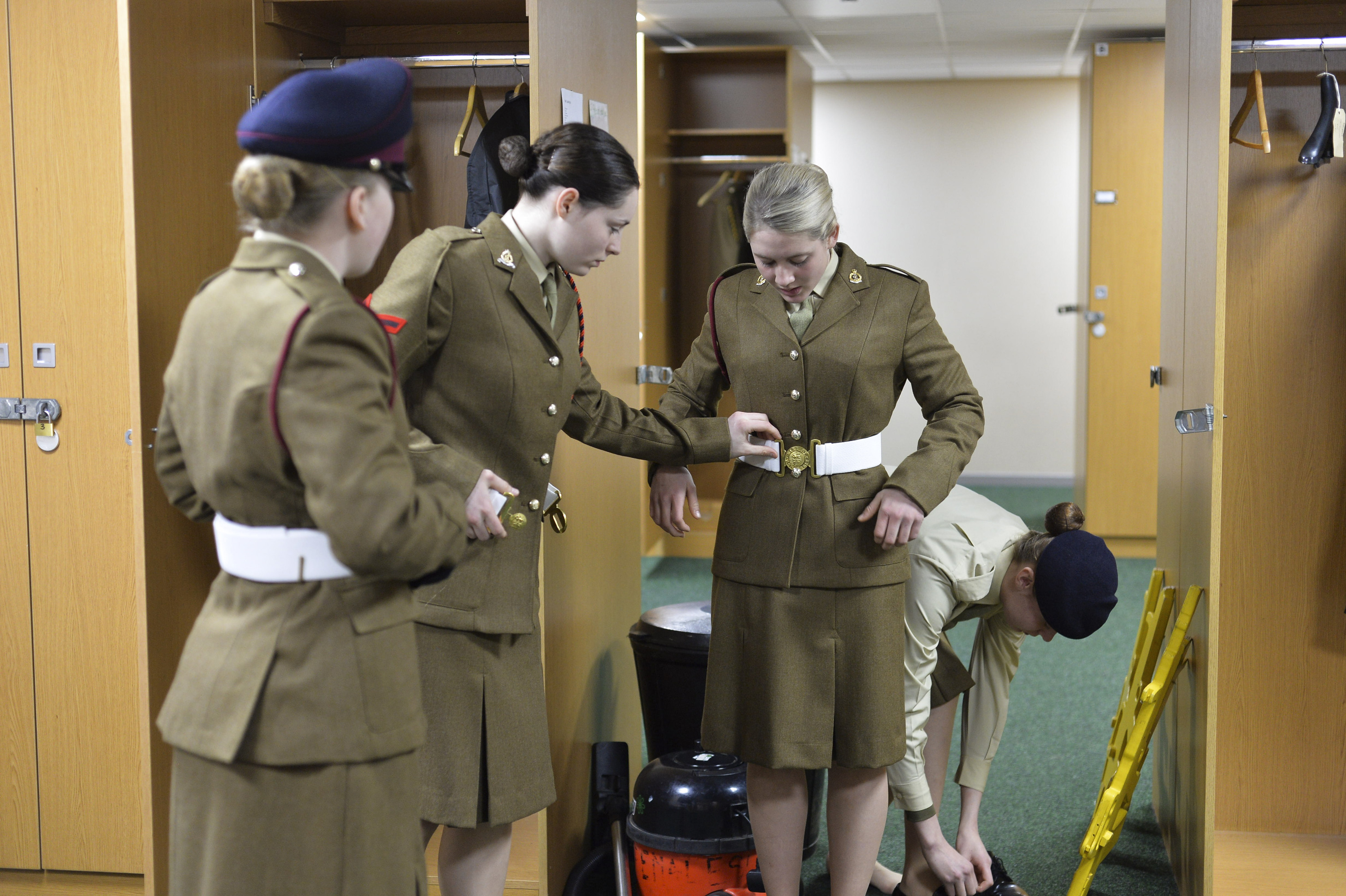 Four female soldiers straightening their uniform in changing room