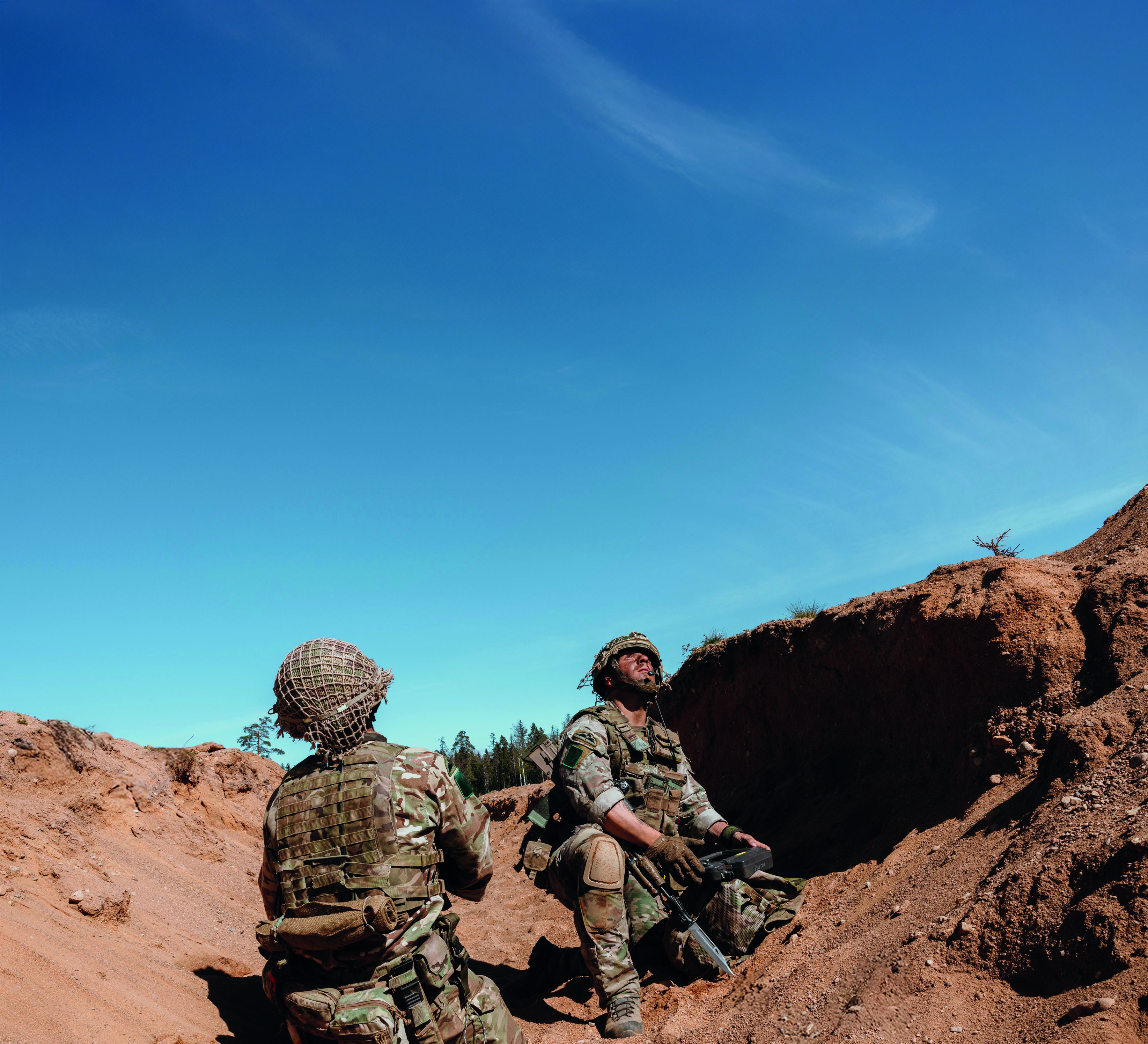 Two soldiers in a sand dune looking up at the sky