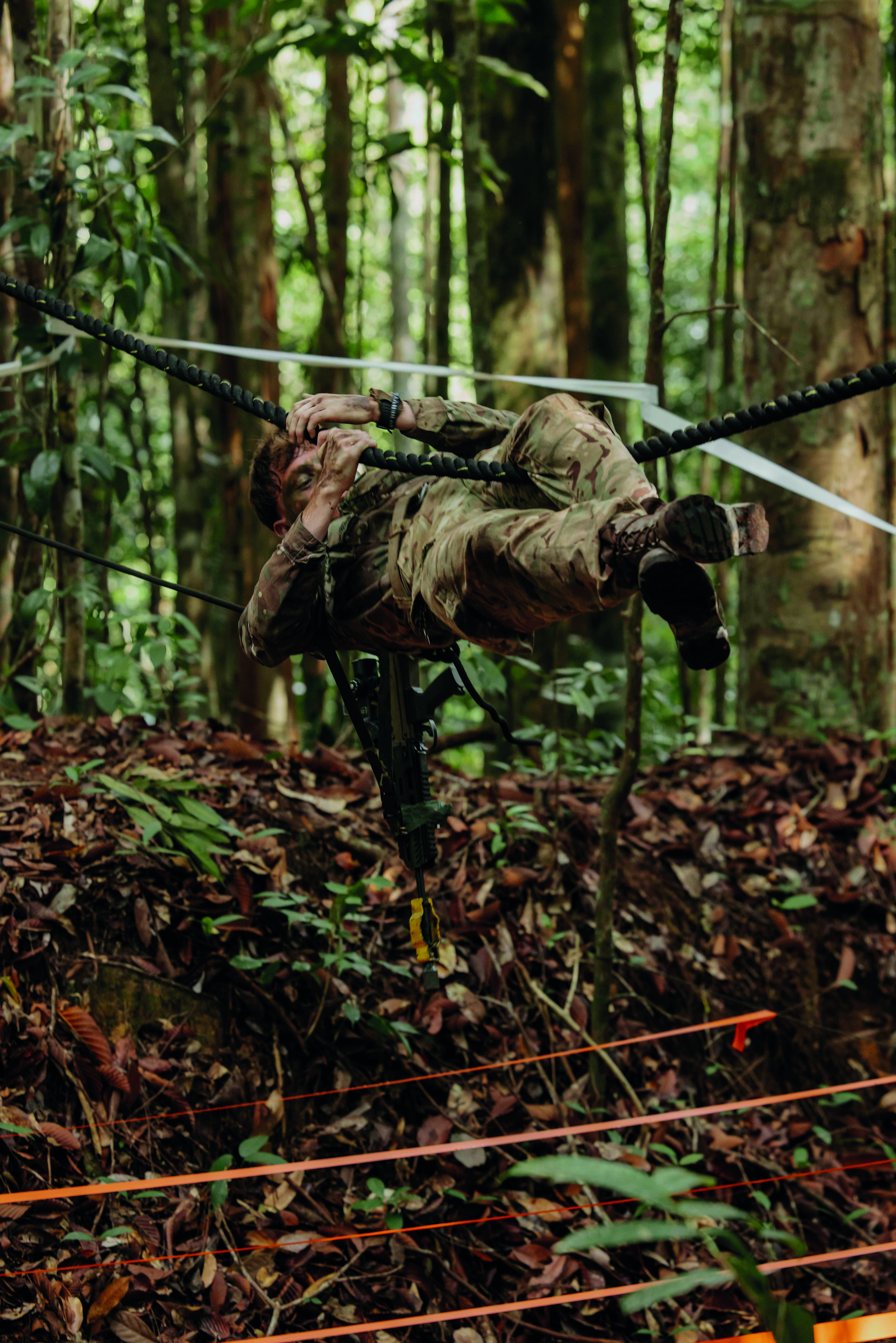 Soldier hanging in horizontal position navigating a rope obstacle 