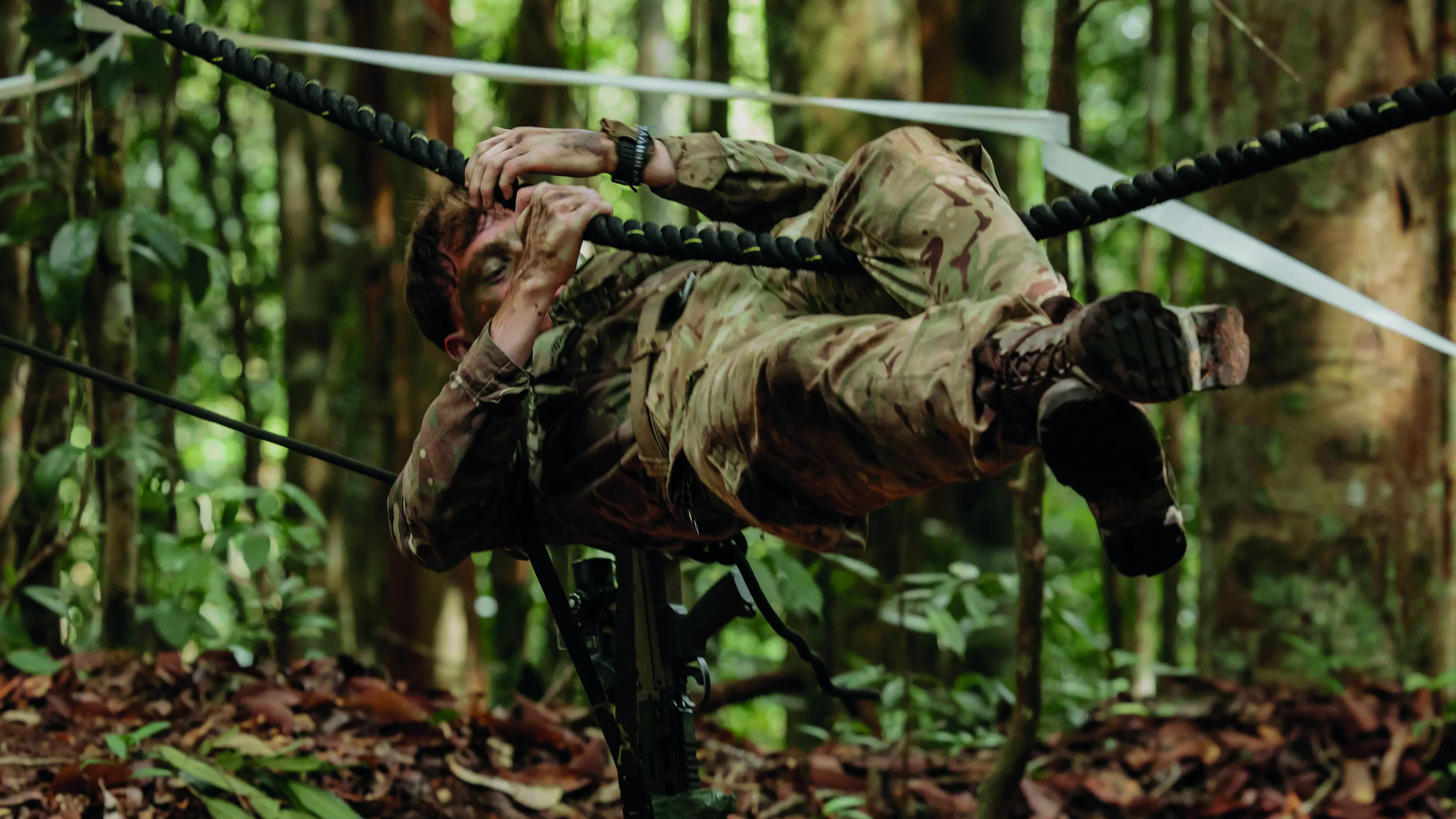 Soldier hanging in horizontal position navigating a rope obstacle