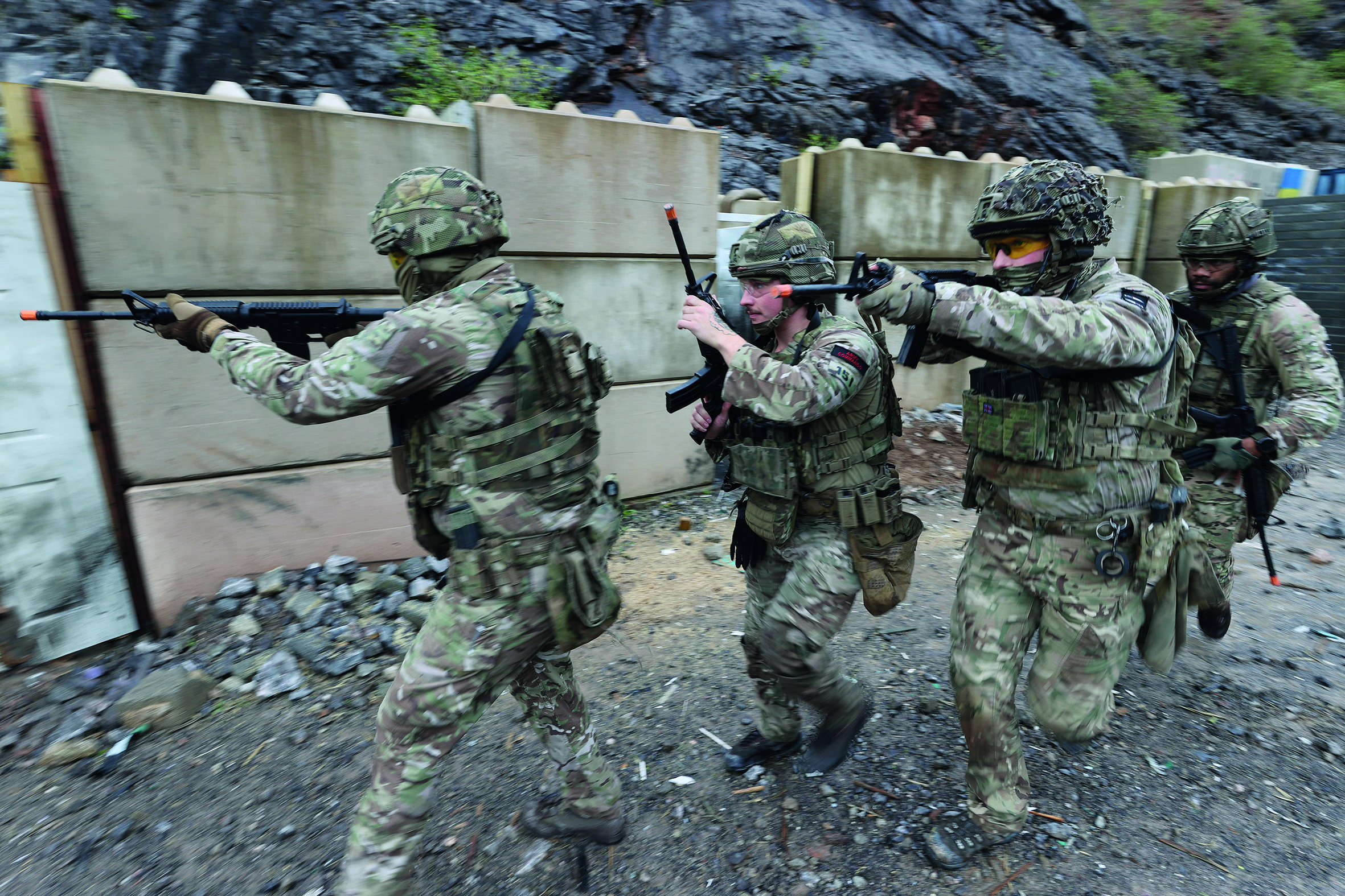Group of soldiers with guns behind a wall of concrete