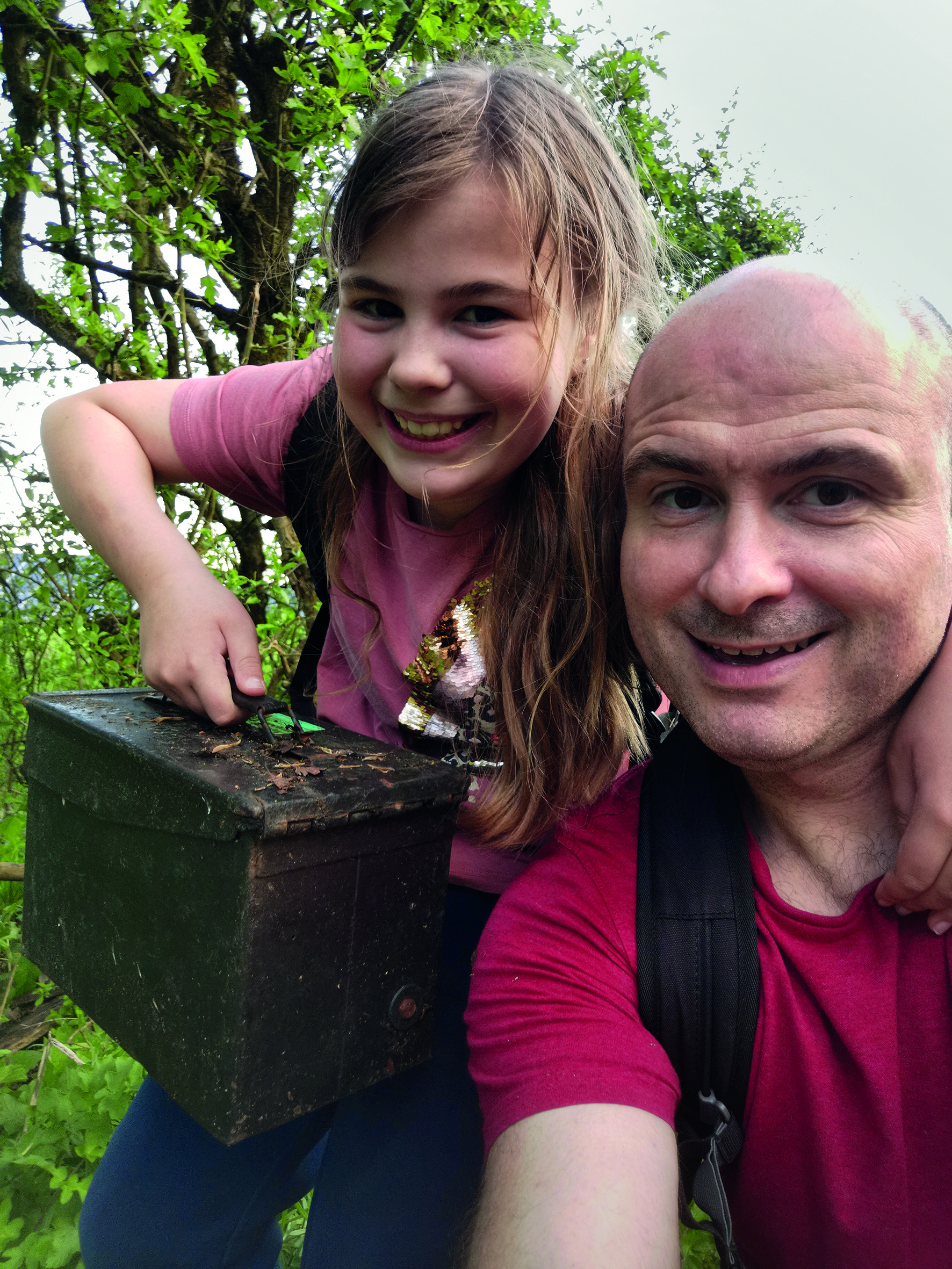 Man and child taking a smiling selfie, the child is holding a box 