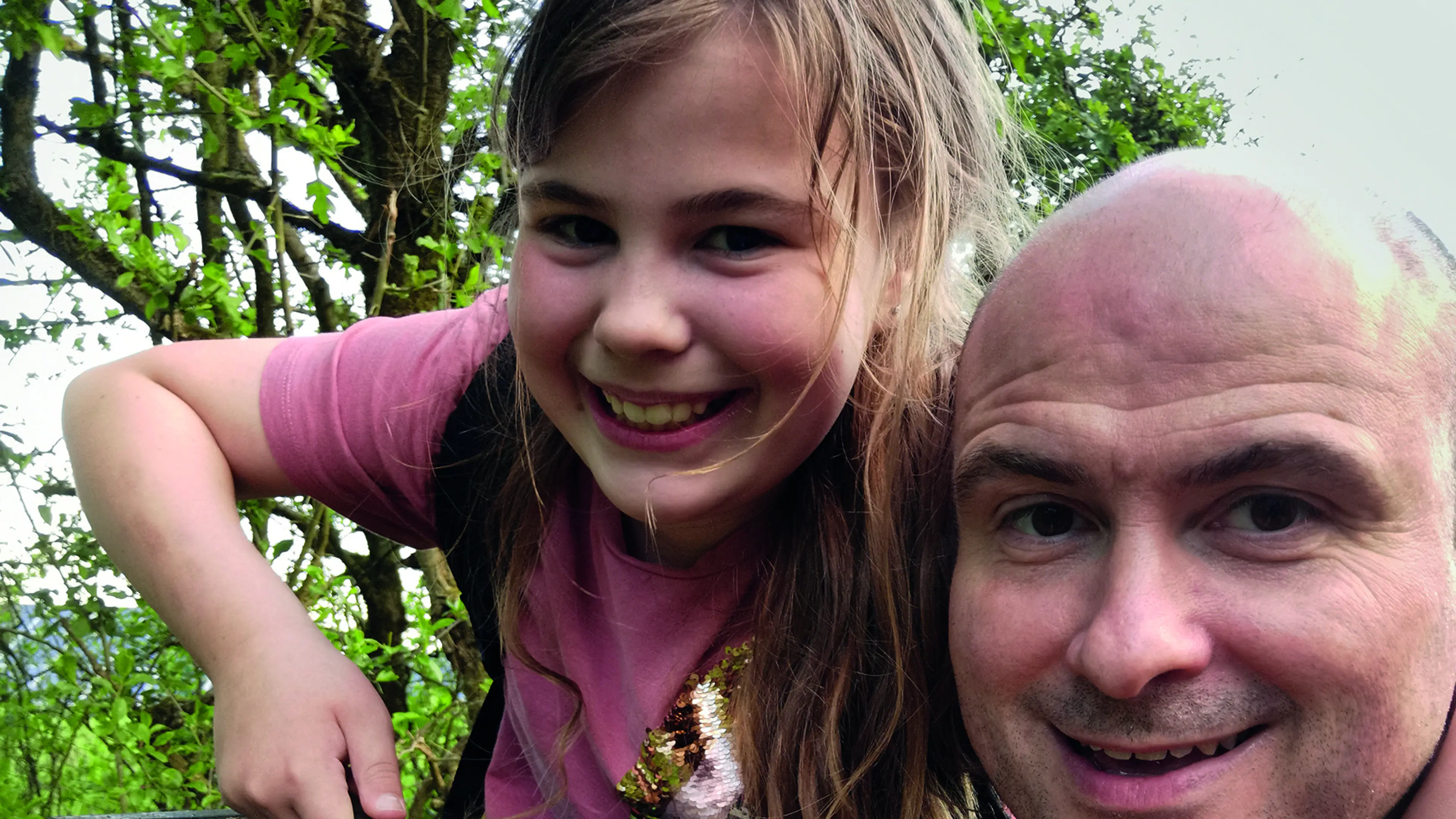 Man and child taking a smiling selfie, the child is holding a box