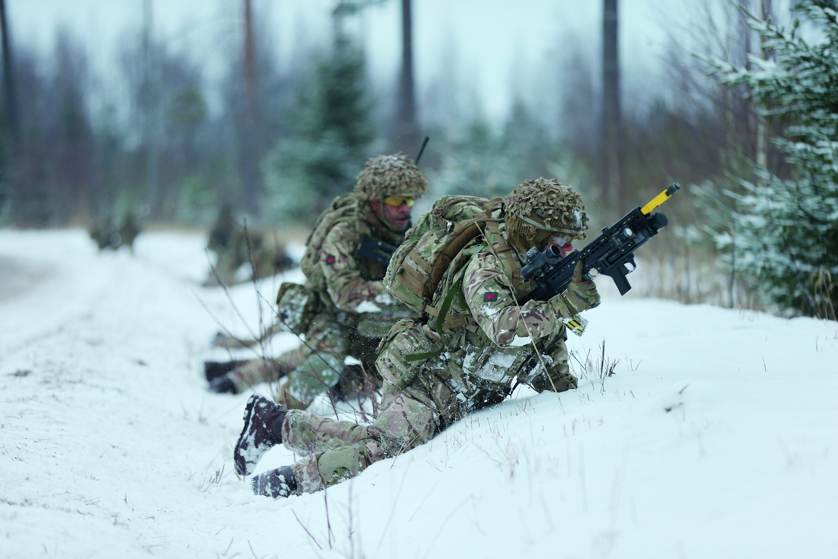 Two soldiers with guns crouching in the snow