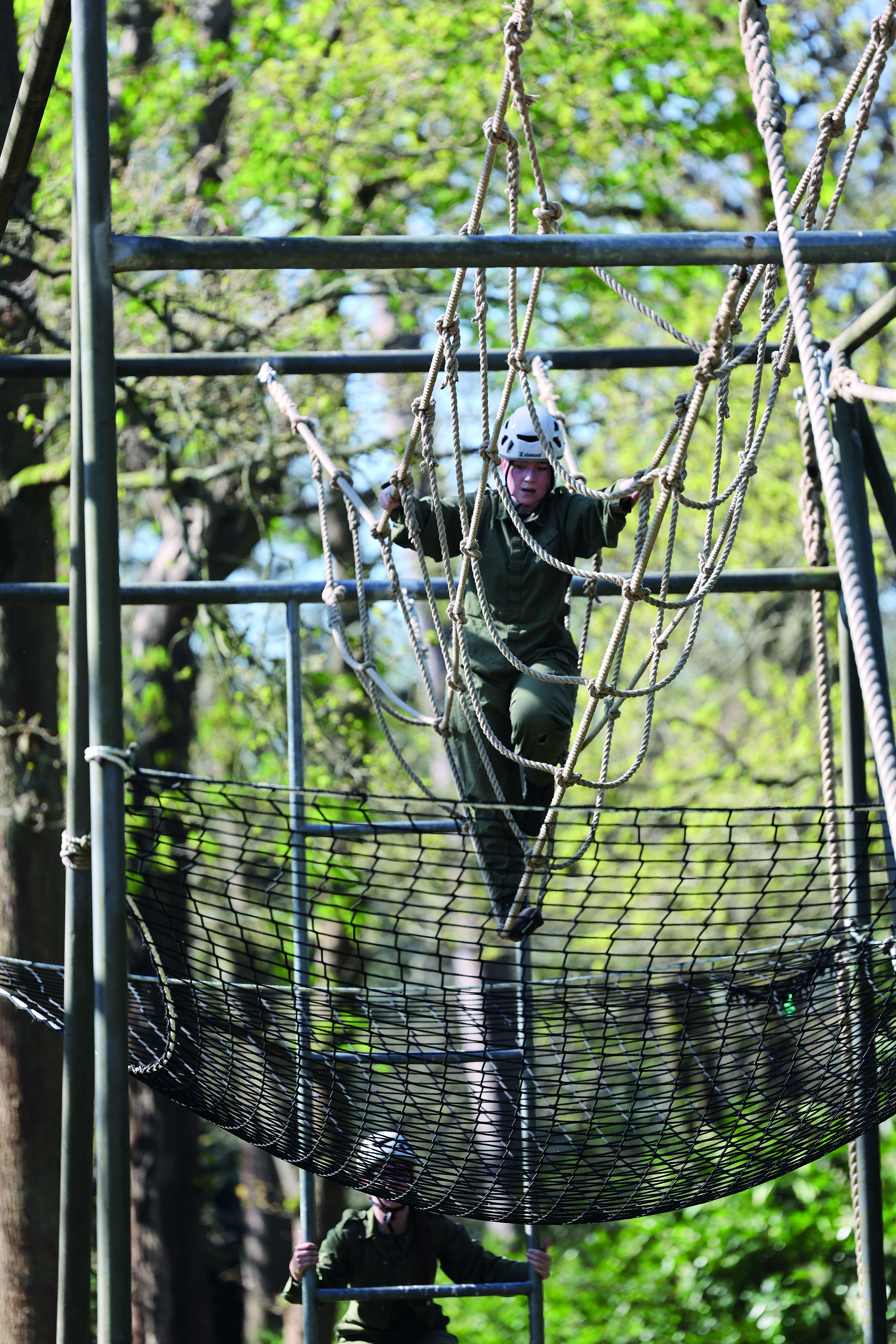 Female cadet, walking across rope bridge in wooded area