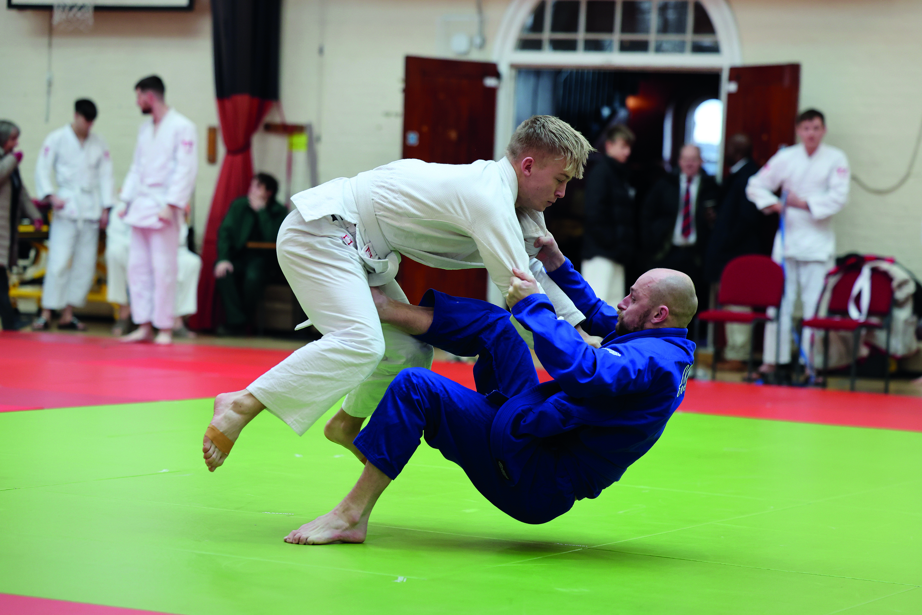 Men practicing judo with onlookers in the background