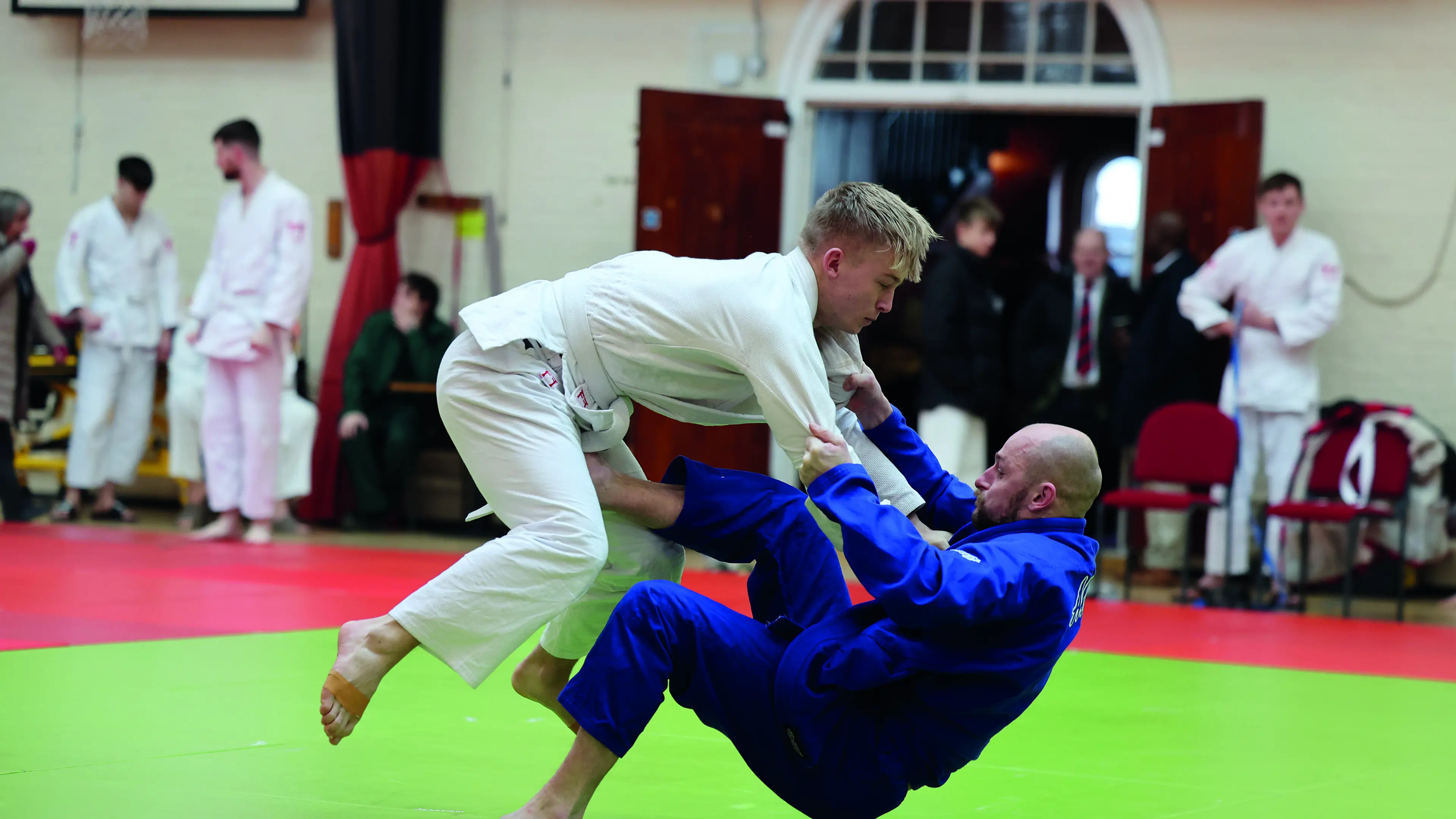 Men practicing judo with onlookers in the background