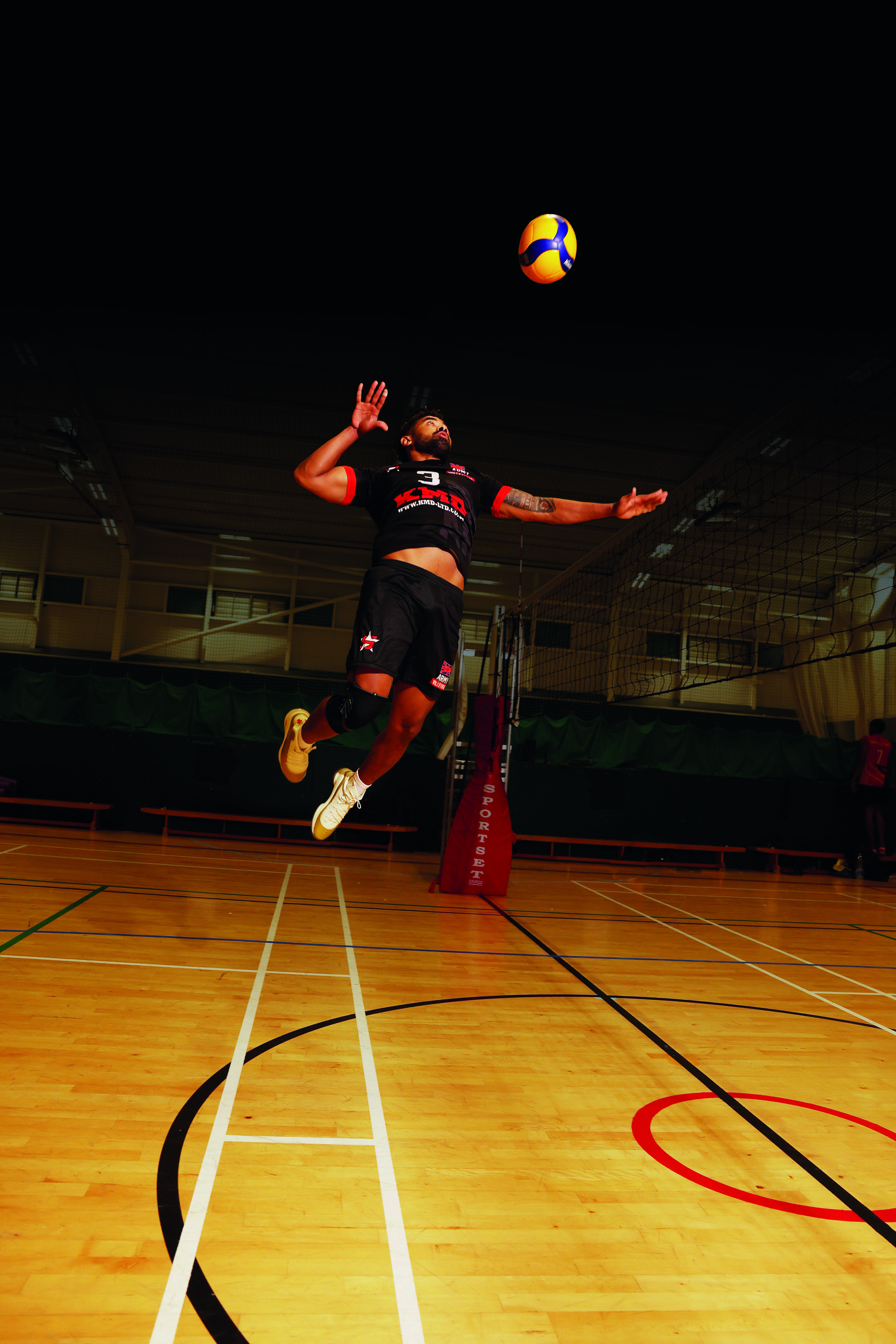 Male volleyball player hitting ball over net
