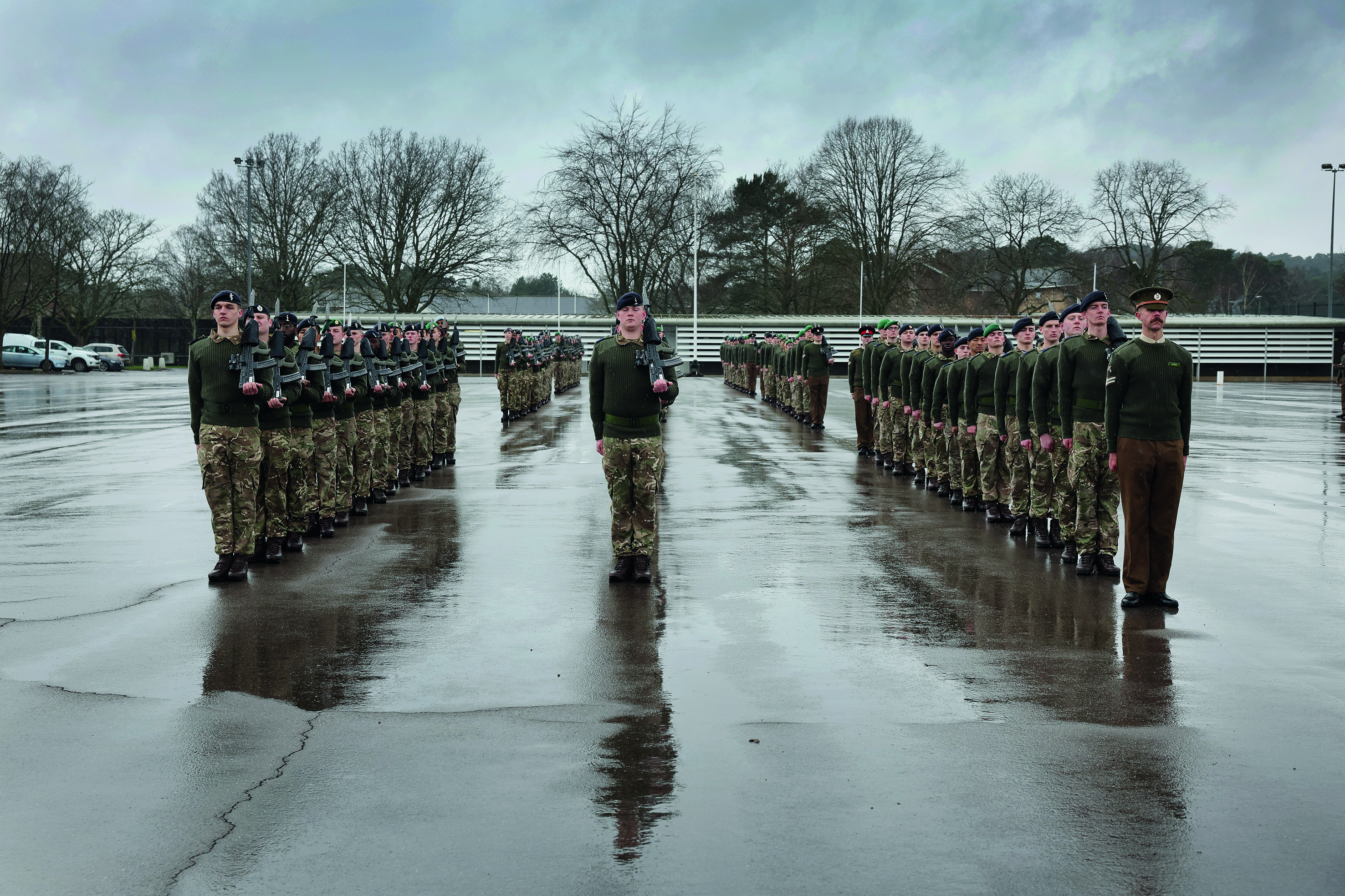 Three lines of soldiers stood in formation wearing military uniform 
