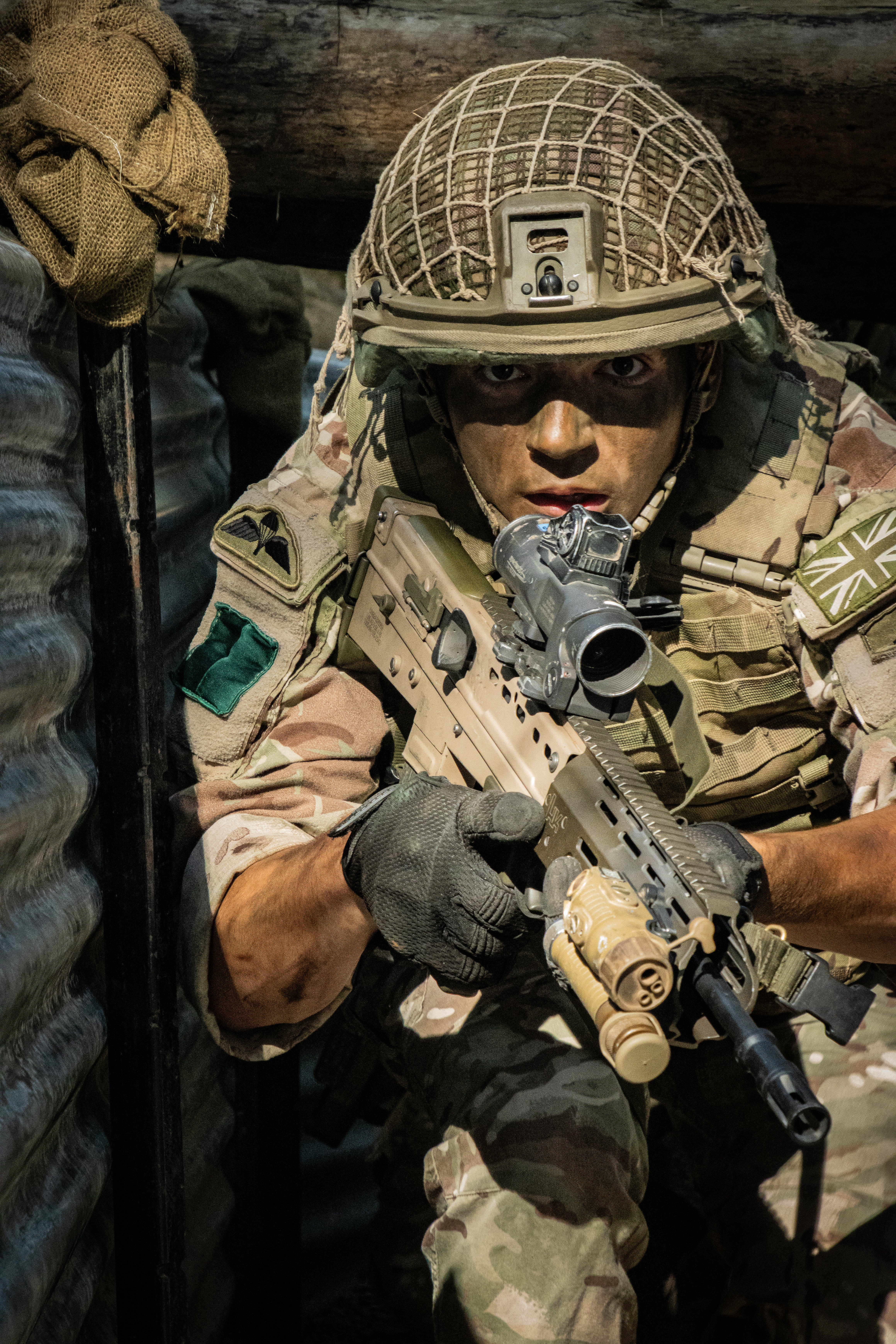 Uniformed and camouflaged female soldier holding gun and staring directly