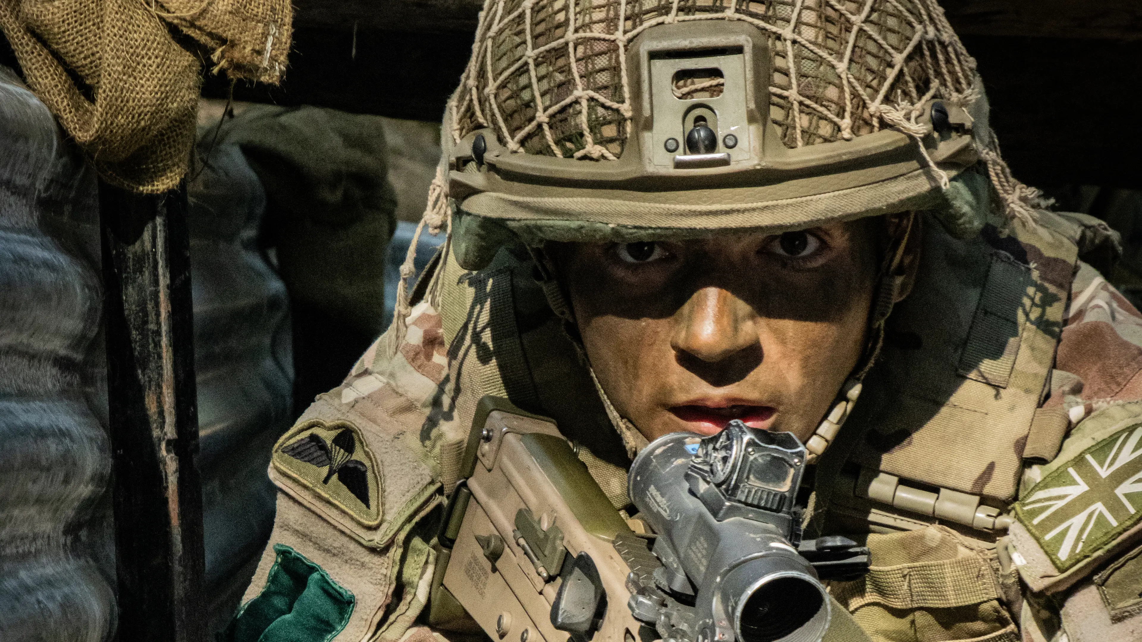 Uniformed and camouflaged female soldier holding gun and staring directly